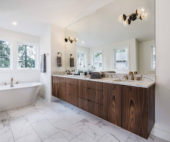 Dark stained cabinet double vanity in a marble tile floor bathroom with a freestanding soaking tub