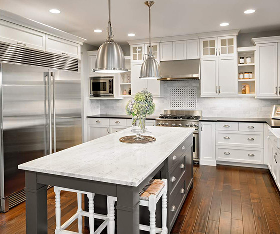 Large kitchen with marble countertops and white recessed cabinets