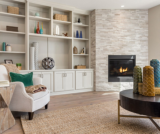 Living room with light hardwood flooring and bookshelf and stone fireplace