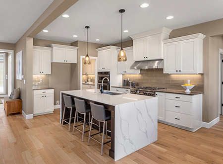 Open concept kitchen with marble island and white cabinets and light hardwood floor