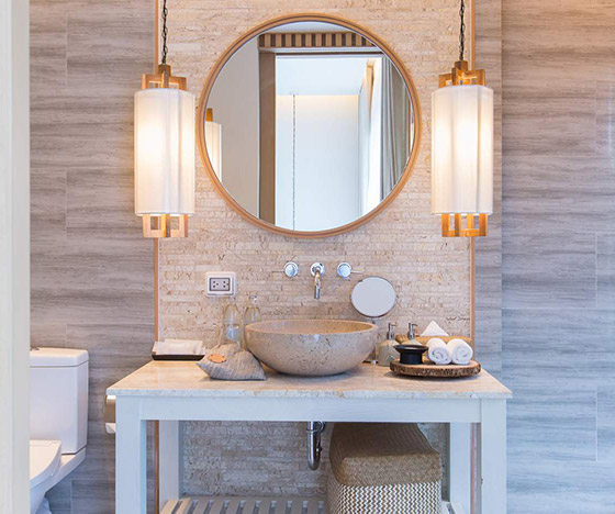 Guest bathroom vanity with vessel sink and open storage beneath it and a circular mirror