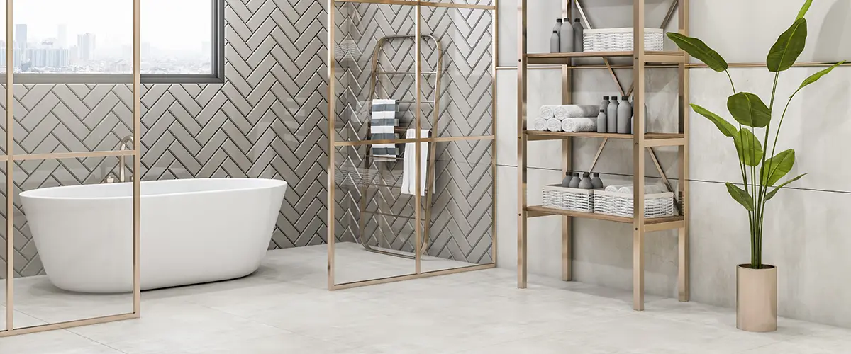 A bathroom with gray tile flooring, tub and shower, and a plant