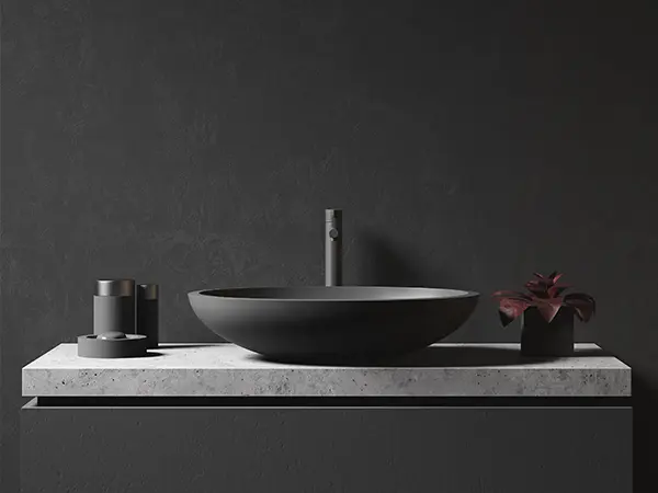 A black vessel sink with a gray countertop