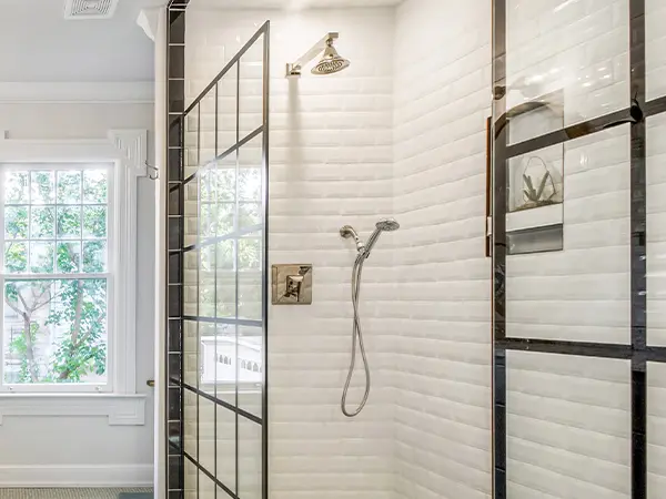 A glass walk-in shower with white tile surround