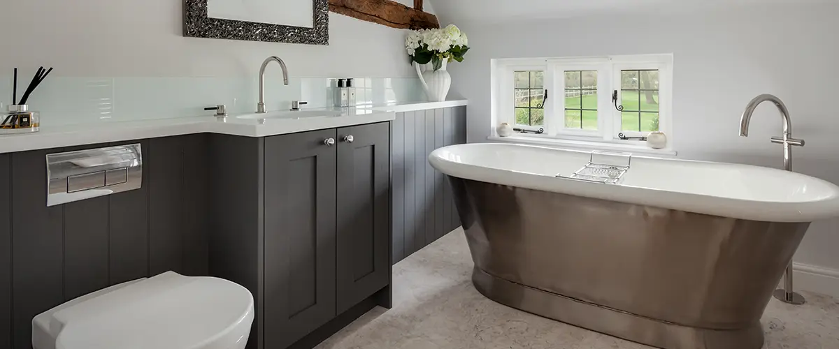 A gray, double vanity with a large freestanding tub