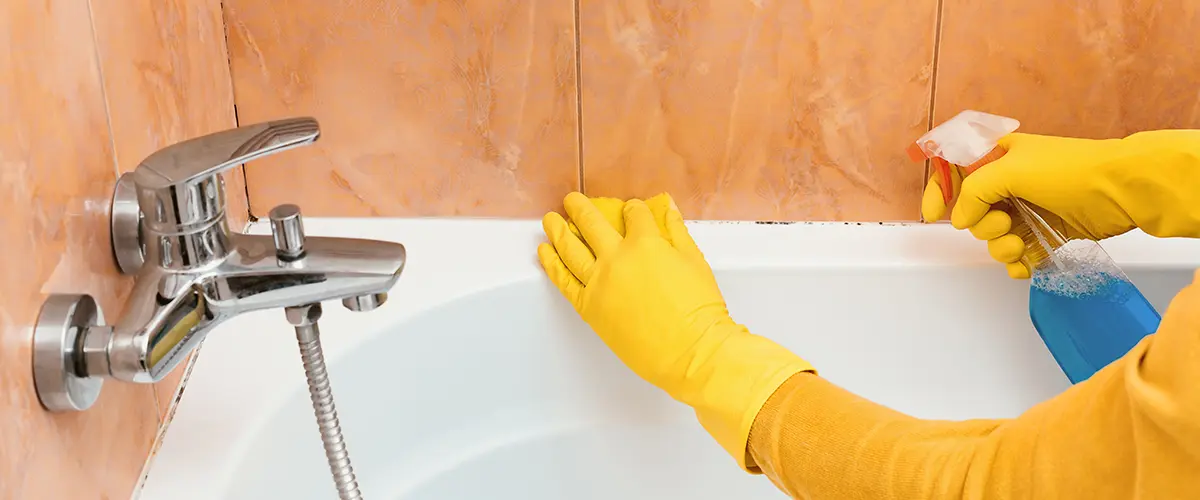 A woman cleaning mold in a shower