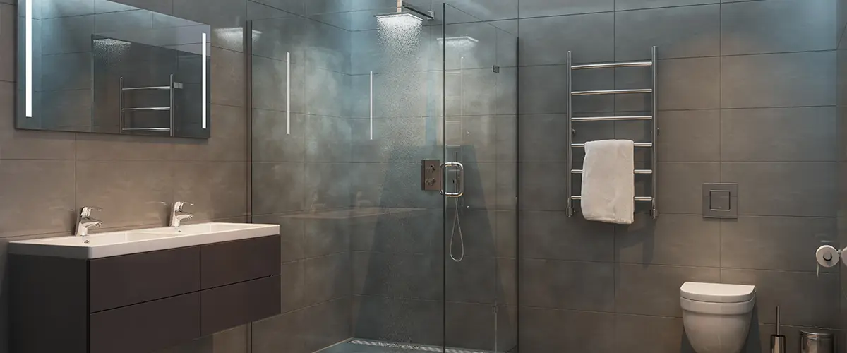 A glass walk-in shower in a large bathroom with gray tile floor and walls