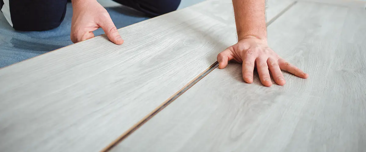 man installing laminate flooring in bathroom