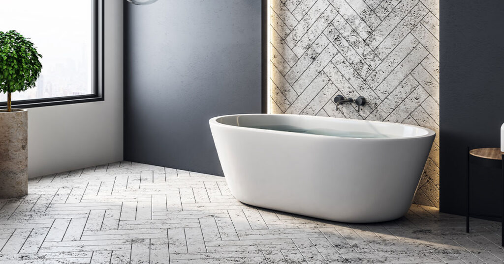 Modern bathroom with a freestanding tub, herringbone tile accent wall, and stylish pendant lights