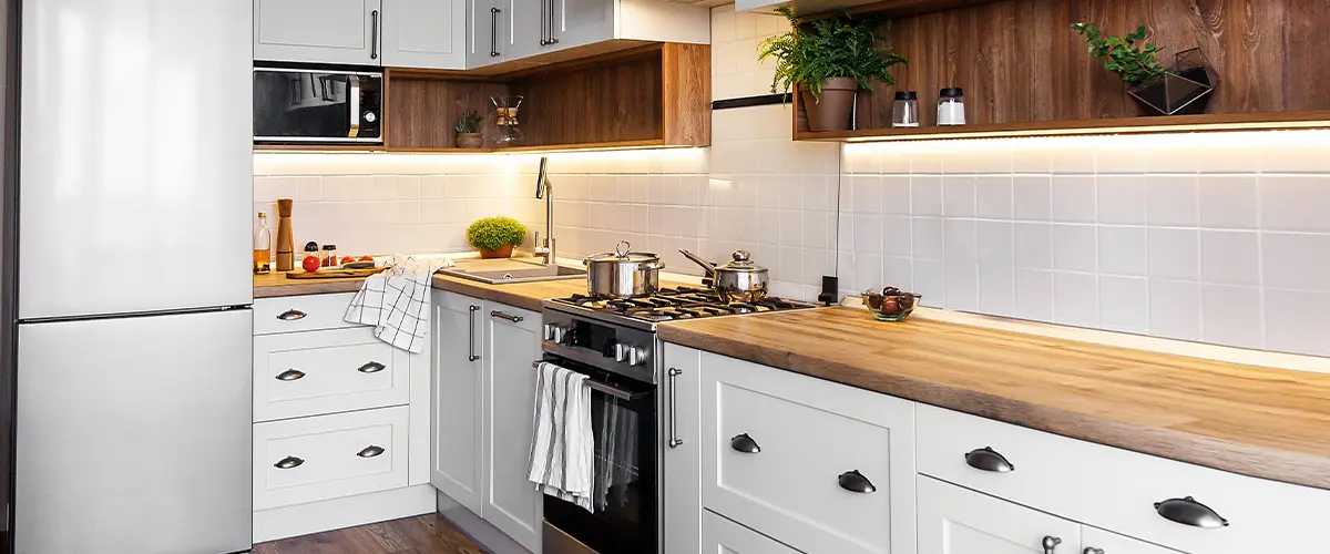 Contemporary kitchen with white cabinets, wood countertops, and under-cabinet lighting for a warm, modern aesthetic.