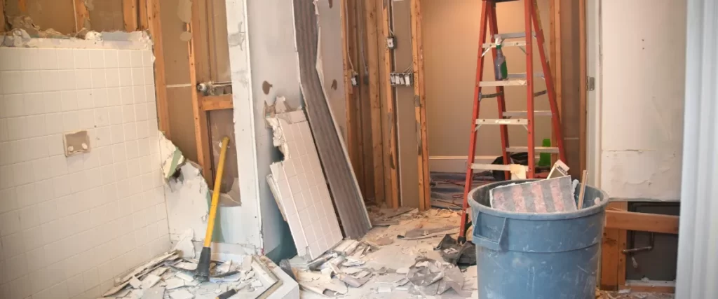 Interior renovation in progress with exposed framing, drywall debris, and construction tools.