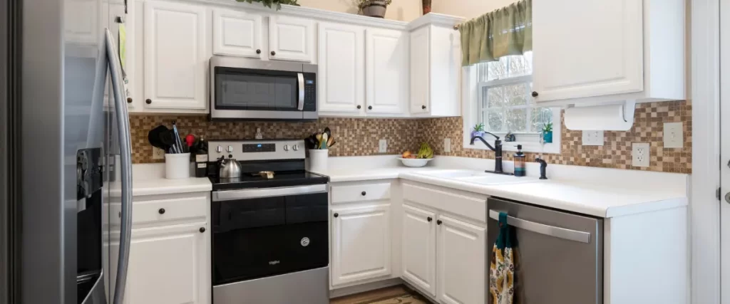 Traditional white kitchen with black appliances, wooden cabinets, and a tiled backsplash.