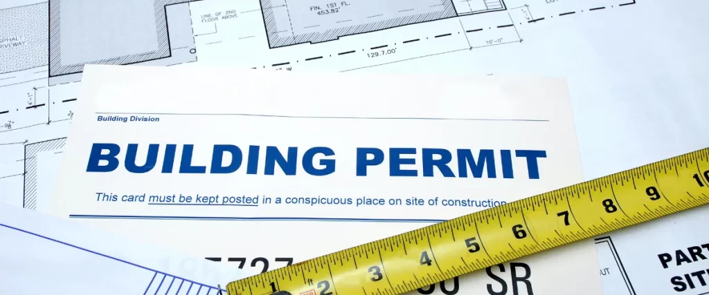 Blueprints and architectural drawings with a building permit document partially visible.