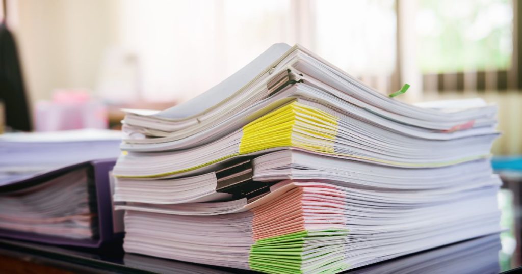 Stack of documents with colorful sticky notes and paper clips, likely related to permits or construction.