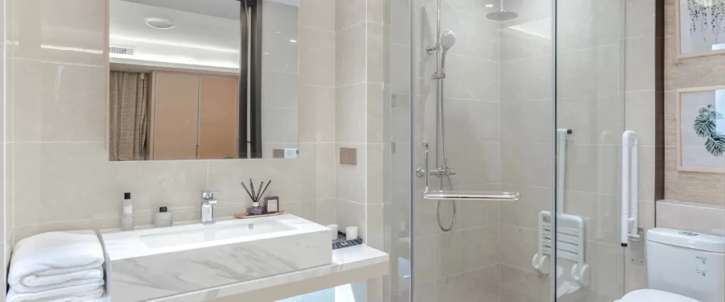 Modern bathroom with a glass shower enclosure, white sink, and a large mirror.