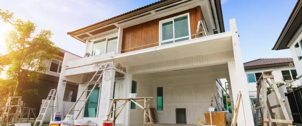 A two-story house under construction or renovation, with scaffolding and construction materials visible (selected).