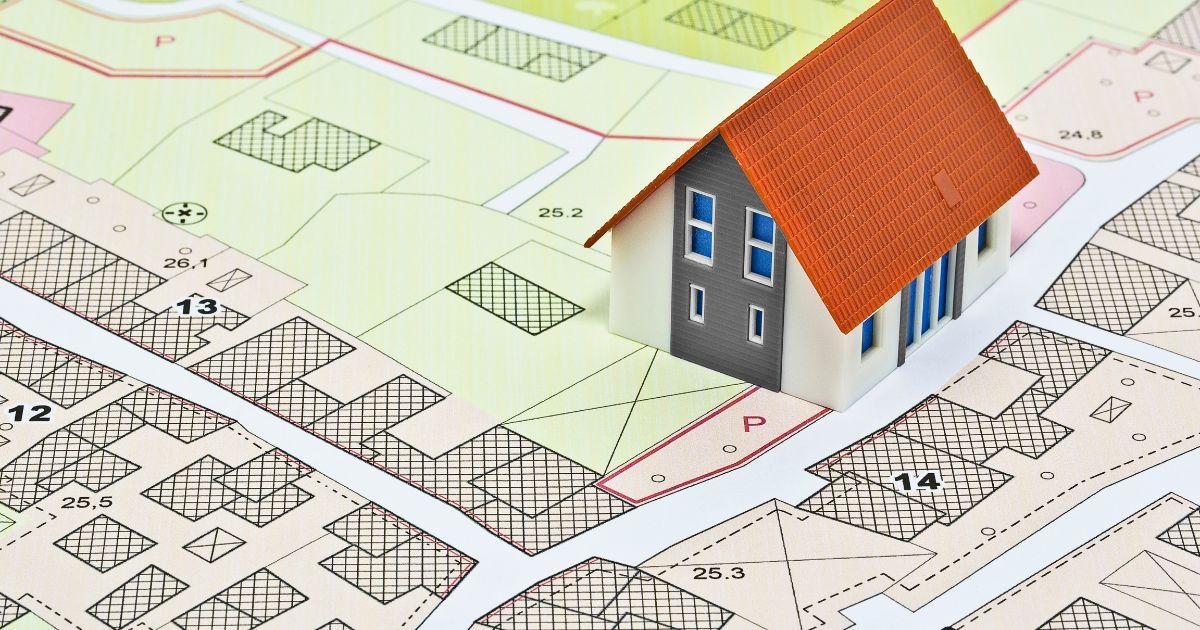 A 3D illustration of a plot map with a small model house placed on one of the lots (selected).