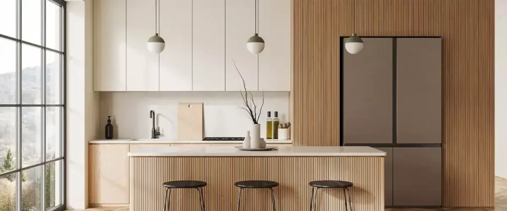 A minimalist, modern kitchen featuring light wood slat paneling and white flat-panel cabinets, with a matte gray, four-door refrigerator and large industrial windows.