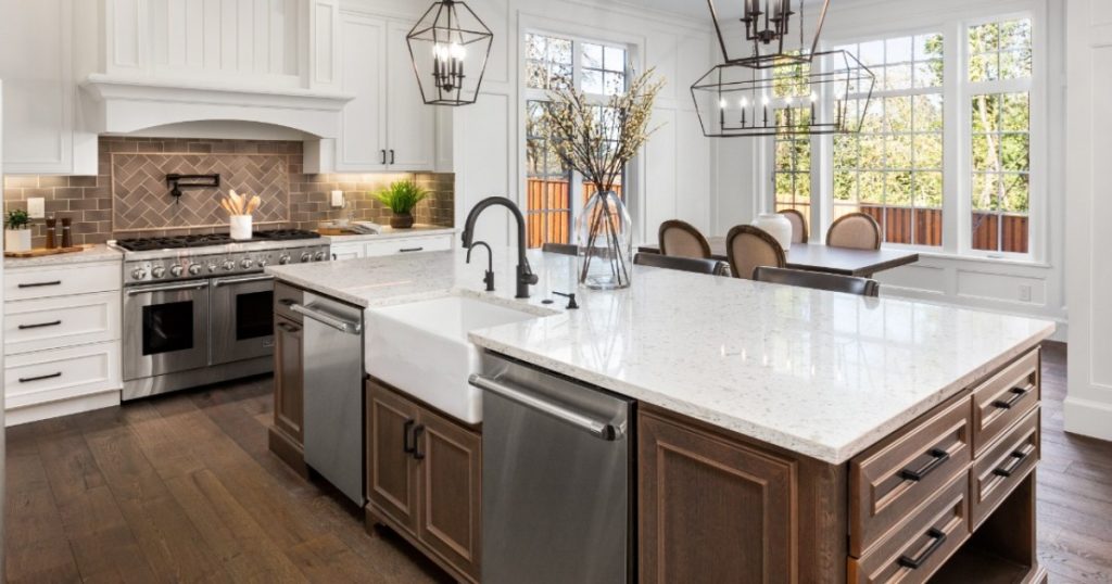 A modern kitchen featuring a spacious island with a sink, surrounded by cabinetry and appliances