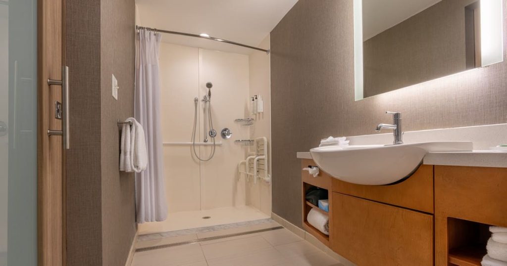A modern, spacious walk-in shower for retirement homes featuring non-slip flooring and safety grab bars.