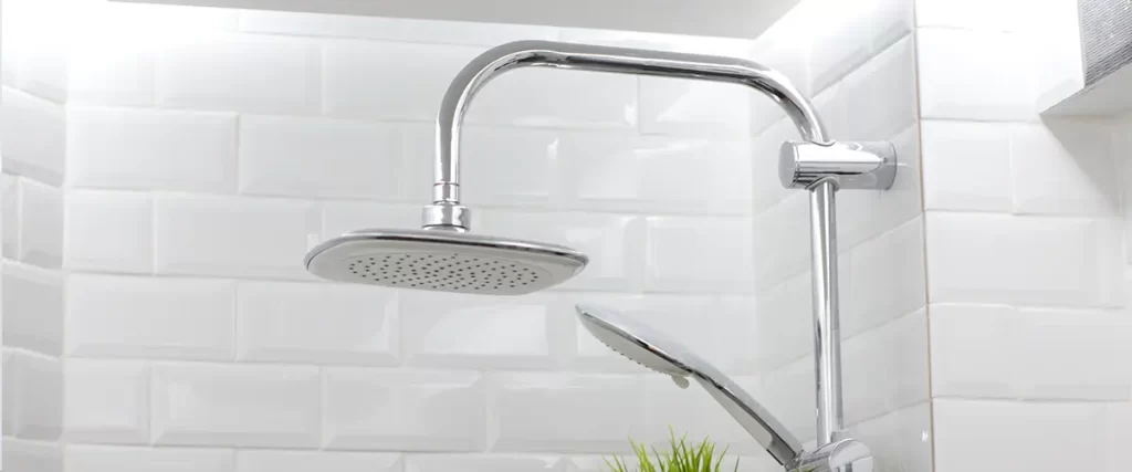 Chrome rainfall shower head with handheld sprayer on white subway tile shower wall