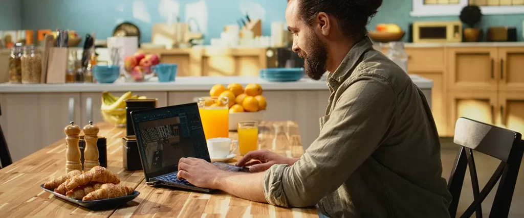 Homeowner reviewing kitchen remodeling design plans on laptop in a modern residential kitchen