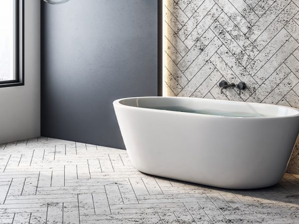 Modern bathroom with a freestanding tub, herringbone tile accent wall, and stylish pendant lights