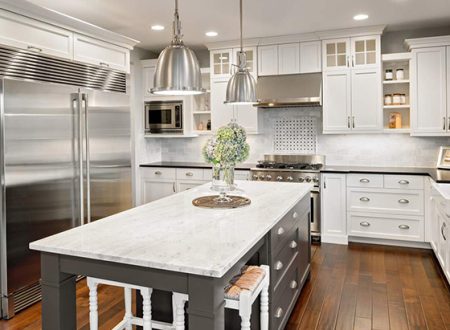 Large kitchen with marble countertops and white recessed cabinets